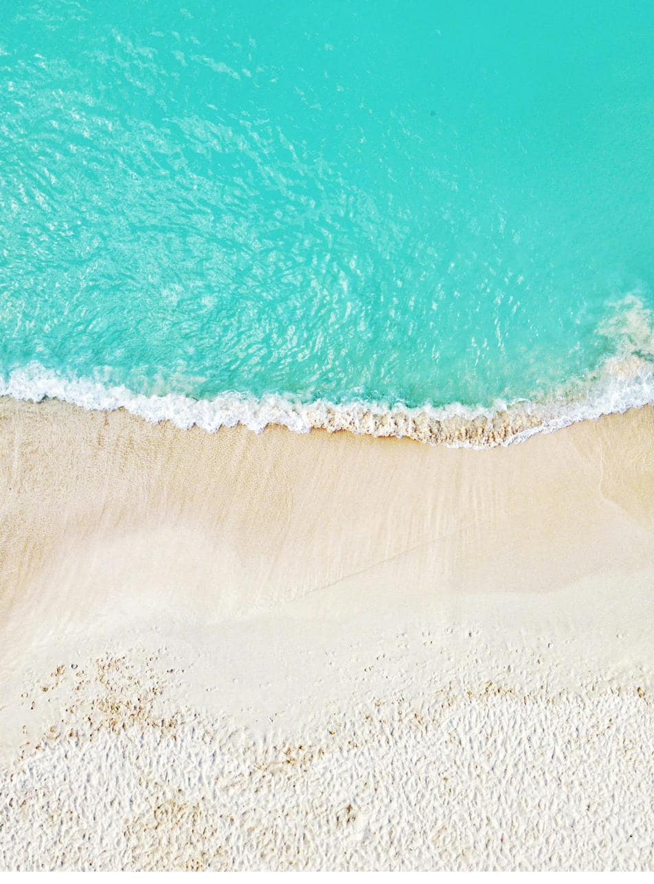Turquoise shallows meeting white sand from above